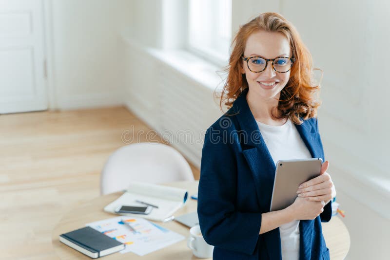 El líder de sexo femenino próspero del equipo de trabajo lleva a cabo el dispositivo digital de la tableta, desarrolla ideas del foto de archivo libre de regalías El líder de sexo femenino próspero del equipo de trabajo lleva a cabo el dispositivo digital de la tableta, desarrolla ideas del foto de archivo libre de regalías
