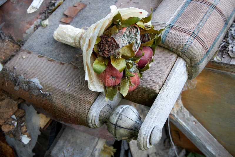 El manojo de fruta putrefacta y las flores marchitadas ponen en los remanente de los muebles quebrados foto de archivo libre de regalías El manojo de fruta putrefacta y las flores marchitadas ponen en los remanente de los muebles quebrados foto de archivo libre de regalías