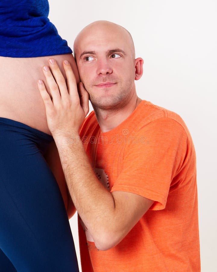 El marido oye por casualidad en el vientre de su esposa foto de archivo libre de regalías El marido oye por casualidad en el vientre de su esposa foto de archivo libre de regalías