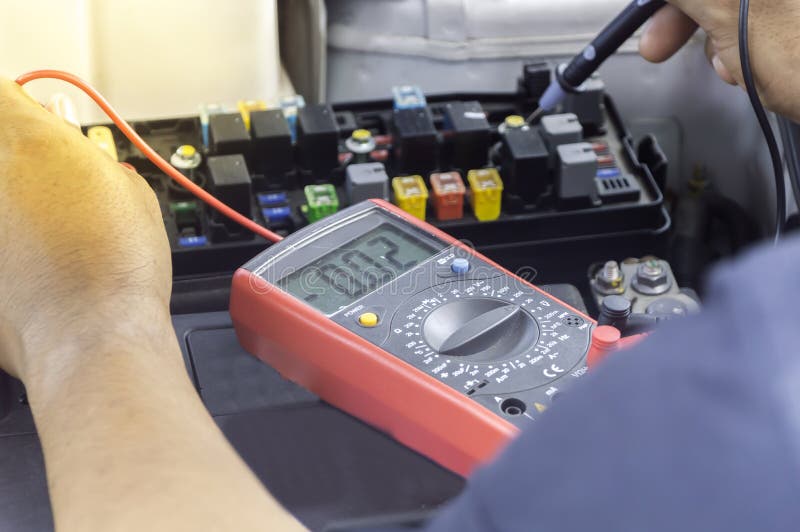 El mecánico de automóviles utiliza un voltímetro del multímetro fotos de archivo libres de regalías El mecánico de automóviles utiliza un voltímetro del multímetro fotos de archivo libres de regalías