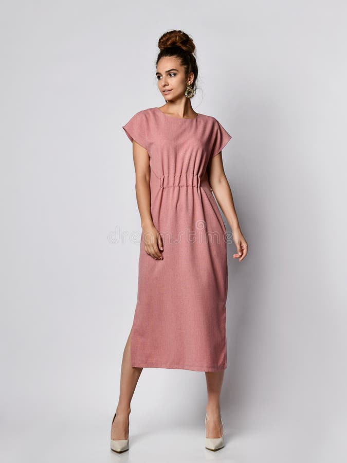 El modelo femenino en un de seda palidece - el vestido largo rosado que mira la cámara en crecimiento completo La muchacha bonita fotografía de archivo libre de regalías El modelo femenino en un de seda palidece - el vestido largo rosado que mira la cámara en crecimiento completo La muchacha bonita fotografía de archivo libre de regalías