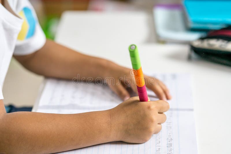 El muchacho asiático joven escribe en el cuaderno por el lápiz en el cuarto fotografía de archivo libre de regalías El muchacho asiático joven escribe en el cuaderno por el lápiz en el cuarto fotografía de archivo libre de regalías
