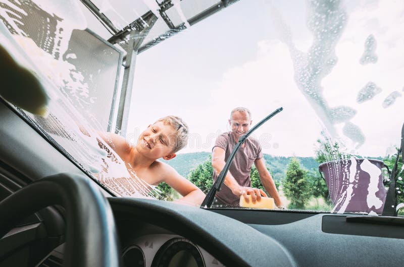 El muchacho ayuda a su padre con el lavado del coche fotografía de archivo El muchacho ayuda a su padre con el lavado del coche fotografía de archivo