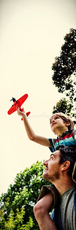 El muchacho con el avión del juguete que se sienta en padres lleva a hombros imagenes de archivo El muchacho con el avión del juguete que se sienta en padres lleva a hombros imagenes de archivo
