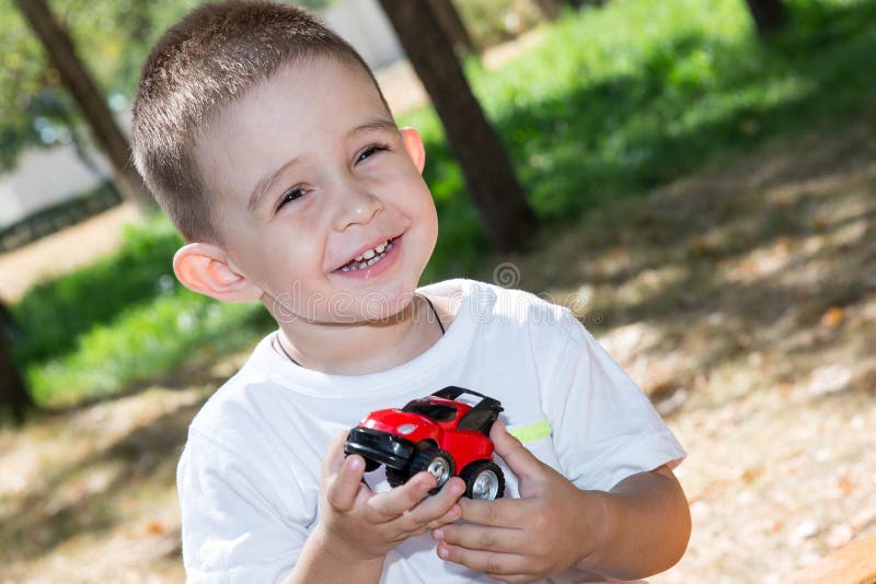 El muchacho lindo del pequeño niño juega con el coche del juguete en parque en la naturaleza en el verano fotos de archivo El muchacho lindo del pequeño niño juega con el coche del juguete en parque en la naturaleza en el verano fotos de archivo
