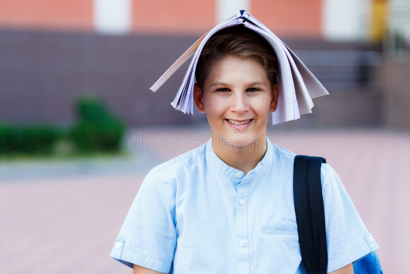 El muchacho lindo, joven en camisa azul con la mochila puso su libro de trabajo en el suyo va a la diversión Él sonríe y se coloc imagenes de archivo El muchacho lindo, joven en camisa azul con la mochila puso su libro de trabajo en el suyo va a la diversión Él sonríe y se coloc imagenes de archivo
