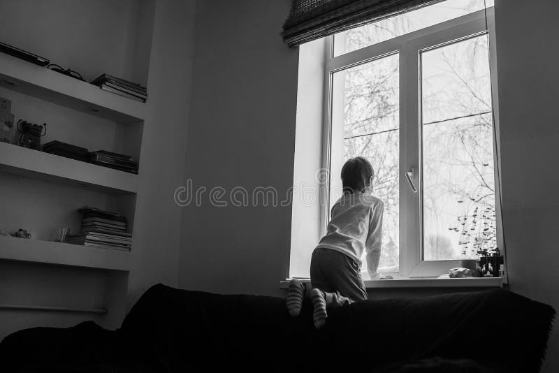 El muchacho mira hacia fuera la ventana en un día de invierno fotos de archivo libres de regalías El muchacho mira hacia fuera la ventana en un día de invierno fotos de archivo libres de regalías