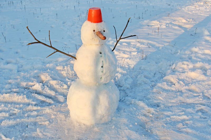 El muñeco de nieve divertido con una nariz de la zanahoria, con un cubo rojo en su cabeza y las palillo-manos en un invierno parq fotografía de archivo libre de regalías El muñeco de nieve divertido con una nariz de la zanahoria, con un cubo rojo en su cabeza y las palillo-manos en un invierno parq fotografía de archivo libre de regalías