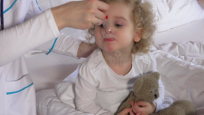 El médico le da jarabe para la tos a la pequeña paciente en su dormitorio 4k