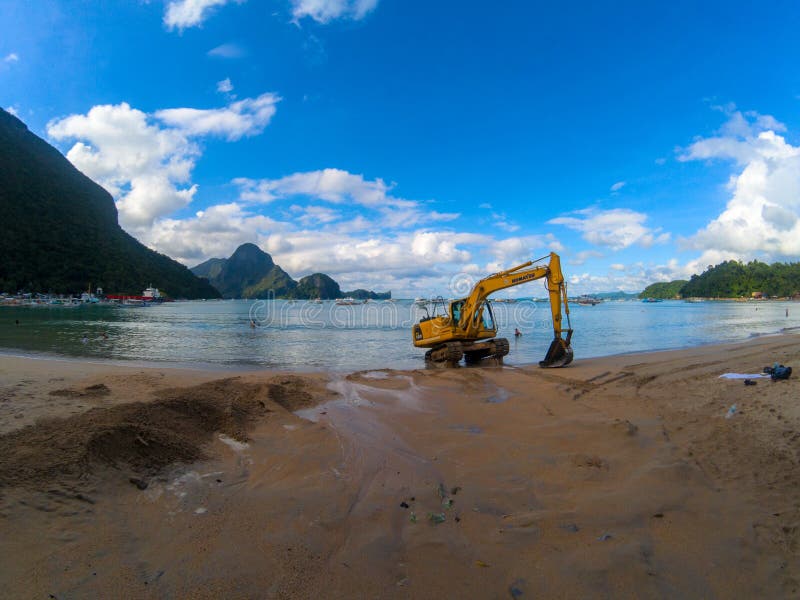 El Nido, Philippines - 21 Nov 2018: sunset beach view with excavator. Cleaning and grooming of tropical seaside royalty free stock photos El Nido, Philippines - 21 Nov 2018: sunset beach view with excavator. Cleaning and grooming of tropical seaside royalty free stock photos