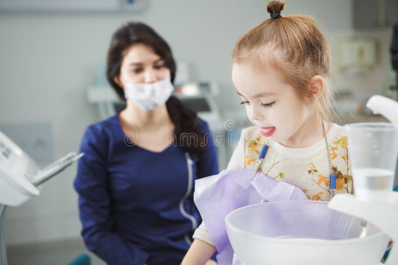 El niño aclara hacia fuera la boca y se sienta en silla del dentista fotografía de archivo libre de regalías El niño aclara hacia fuera la boca y se sienta en silla del dentista fotografía de archivo libre de regalías