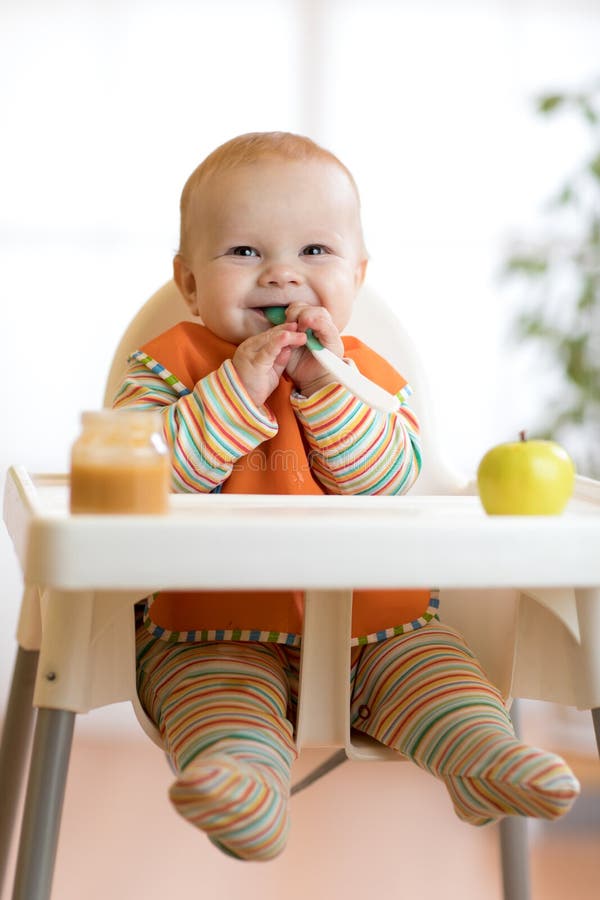 El niño alegre del bebé come la comida sí mismo con la cuchara Retrato del muchacho feliz del niño en trona foto de archivo El niño alegre del bebé come la comida sí mismo con la cuchara Retrato del muchacho feliz del niño en trona foto de archivo