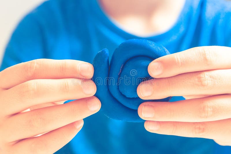 El niño da la elaboración de la figura del juguete con la arcilla de modelado o el plasticine imagen de archivo El niño da la elaboración de la figura del juguete con la arcilla de modelado o el plasticine imagen de archivo