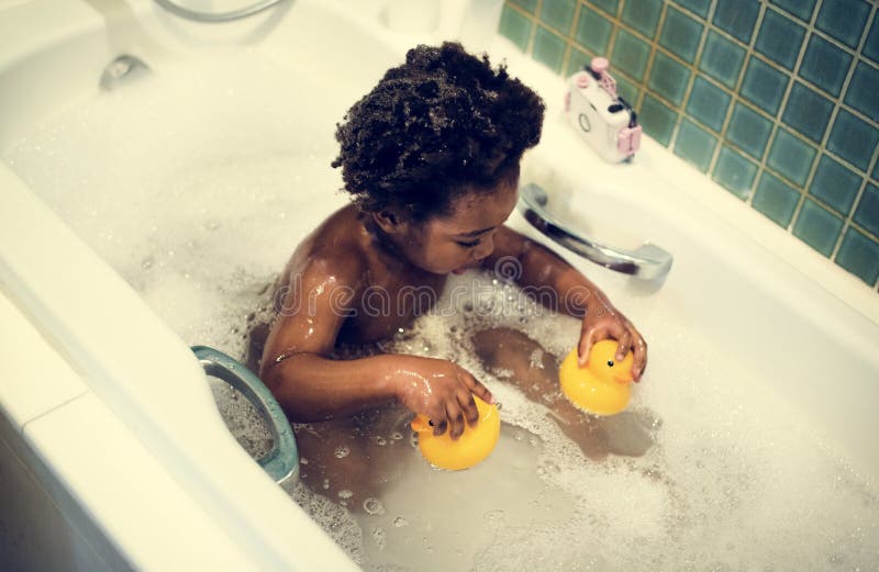 El niño de la ascendencia africana goza el bañarse