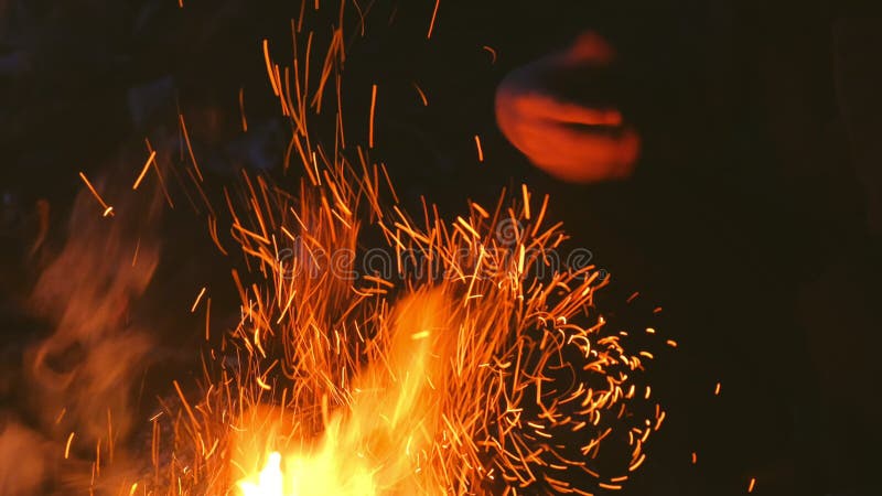 El niño está calentando sus manos sobre el fuego en una fogata acampando en la naturaleza por la noche.