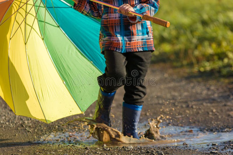 El niño está jugando con el paraguas colorido en un charco fotografía de archivo El niño está jugando con el paraguas colorido en un charco fotografía de archivo