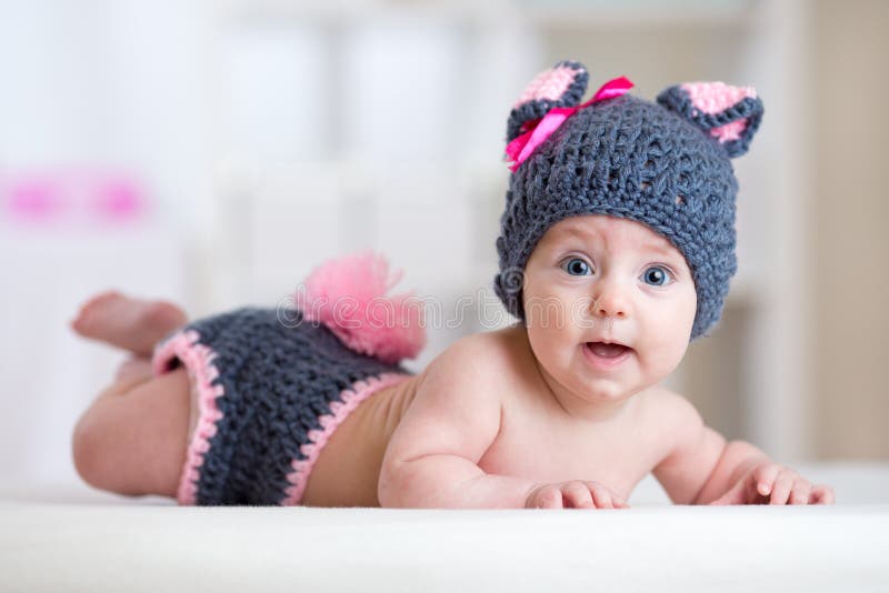 El niño lindo sonriente del bebé en conejo viste la mentira en cuarto de niños fotografía de archivo libre de regalías El niño lindo sonriente del bebé en conejo viste la mentira en cuarto de niños fotografía de archivo libre de regalías