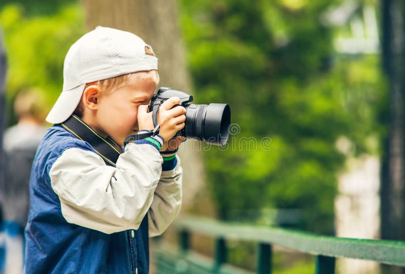 El niño pequeño con la cámara de la foto hace un lanzamiento fotografía de archivo El niño pequeño con la cámara de la foto hace un lanzamiento fotografía de archivo