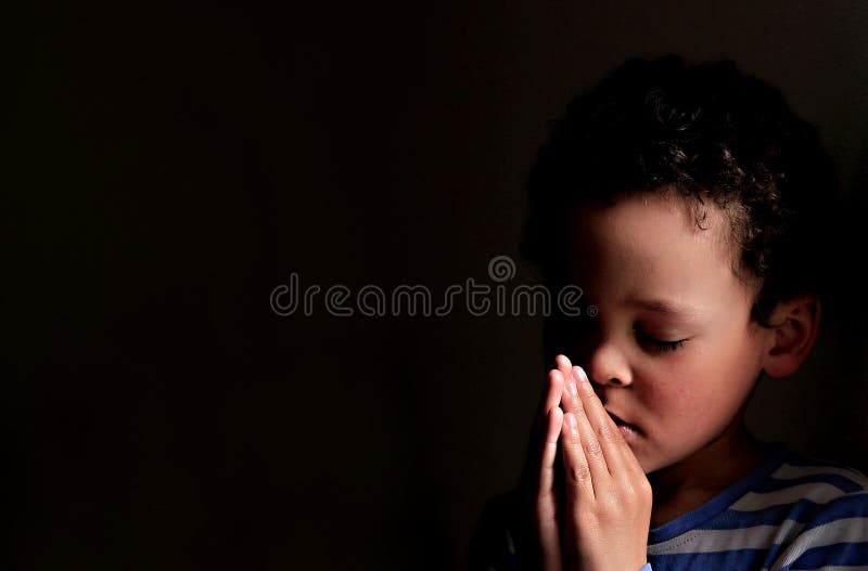 El niño pequeño que rogaba a dios con las manos ligó la foto común
