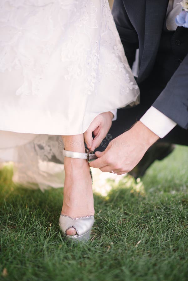 El novio pone a la novia en el zapato del primer del pie foto de archivo El novio pone a la novia en el zapato del primer del pie foto de archivo