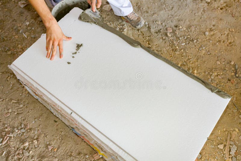 View on worker's hand with trowel, applying glue on thermal insulation material, Styrofoam for insulation the building under construction. View on worker's hand with trowel, applying glue on thermal insulation material, Styrofoam for insulation the building under construction