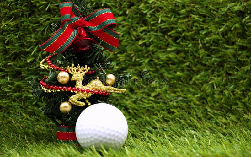 Christmas ornament is on green grass background with one golf ball. Christmas ornament is on green grass background with one golf ball