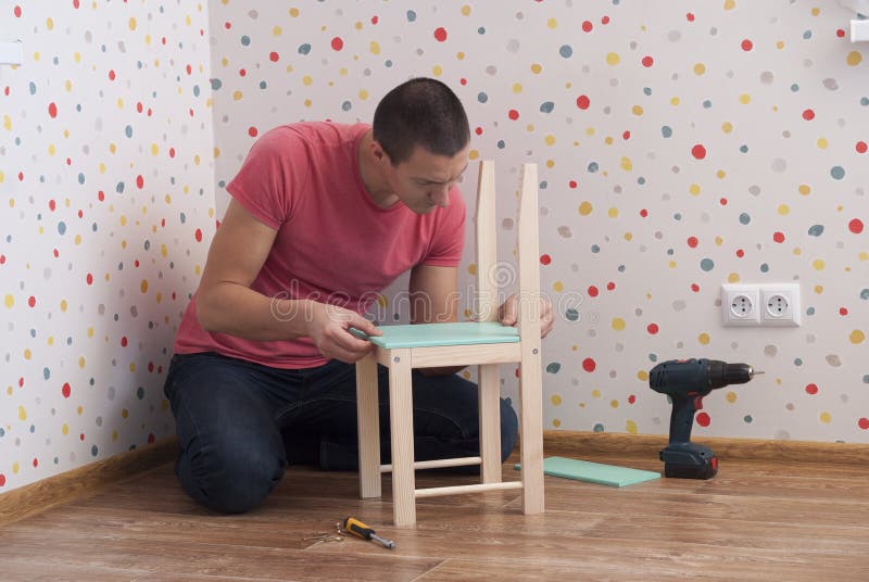 El padre monta una silla para los niños fotos de archivo El padre monta una silla para los niños fotos de archivo