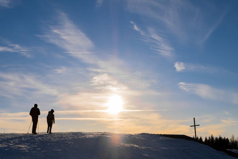 El padre y el hijo que caminan la cumbre de la montaña cruzan con puesta del sol agradable fotografía de archivo libre de regalías El padre y el hijo que caminan la cumbre de la montaña cruzan con puesta del sol agradable fotografía de archivo libre de regalías