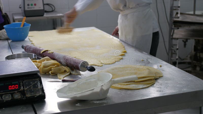 El panadero que anota y que corta los pasteles de la pasta circunda en panadería