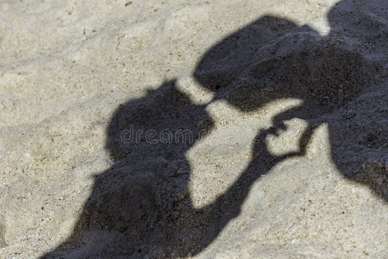 Young loving couple shadows making a kiss on tropical sand beach. Young loving couple shadows making a kiss on tropical sand beach