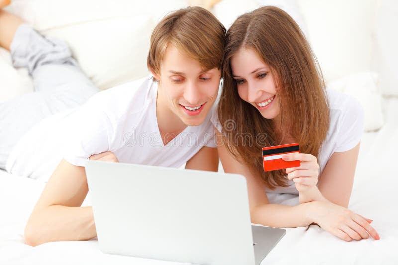 El par feliz hace compras en línea con el ordenador portátil y la tarjeta de crédito a fotos de archivo libres de regalías El par feliz hace compras en línea con el ordenador portátil y la tarjeta de crédito a fotos de archivo libres de regalías