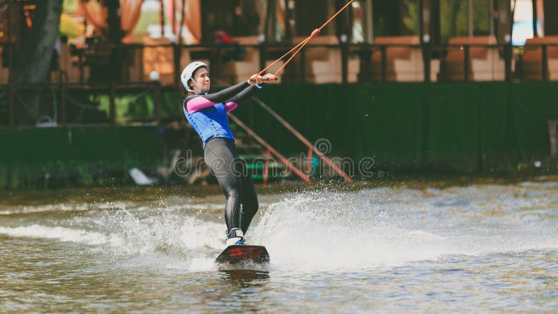 El parque extremo, Kiev, Ucrania, 07 puede 2017 - una chica joven, acostumbrada para montar Wakeboarding Foto del proceso del gra imagen de archivo libre de regalías El parque extremo, Kiev, Ucrania, 07 puede 2017 - una chica joven, acostumbrada para montar Wakeboarding Foto del proceso del gra imagen de archivo libre de regalías