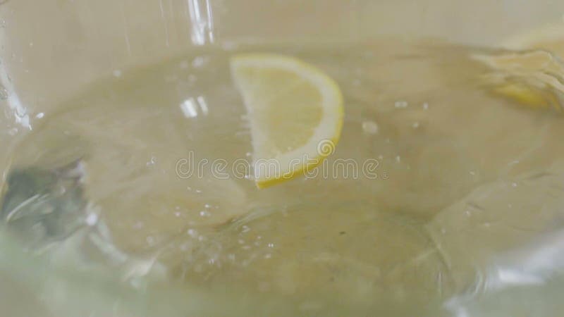 El pedazo de limón cae en bol de vidrio en agua en a cámara lenta