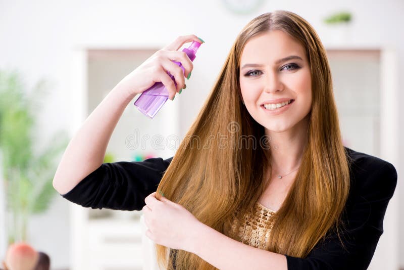 El pelo de rociadura de la mujer joven pule a su pelo imagenes de archivo El pelo de rociadura de la mujer joven pule a su pelo imagenes de archivo