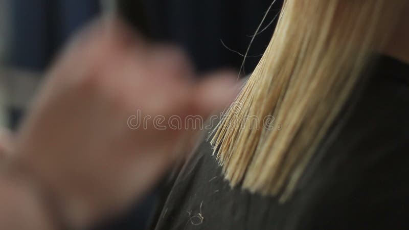 El peluquero esquila a una mujer con el pelo rubio largo Primer del corte de pelo