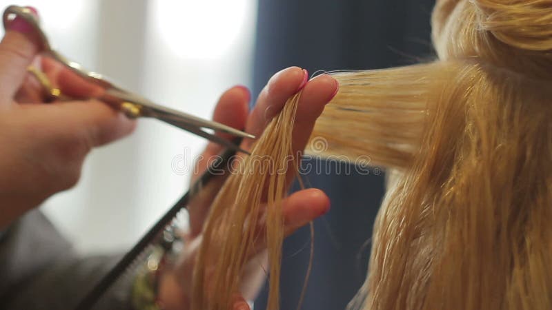El peluquero esquila a una mujer con el pelo rubio largo Primer del corte de pelo