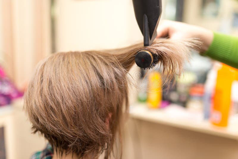 El peluquero seca el pelo rubio del secador de pelo