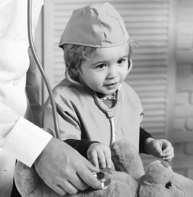El pequeño ayudante examina el oso de peluche Padre y niño con la cara curiosa y feliz que juega al doctor imagenes de archivo El pequeño ayudante examina el oso de peluche Padre y niño con la cara curiosa y feliz que juega al doctor imagenes de archivo