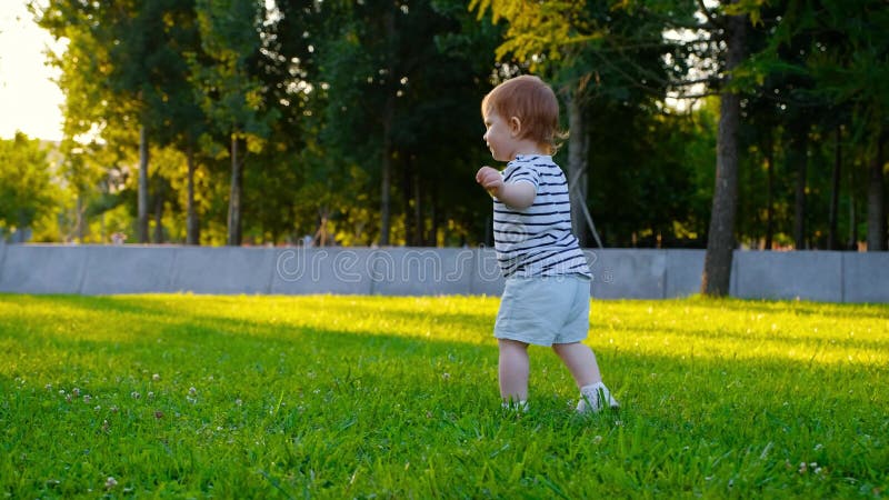 El pequeño bebé lindo camina por la hierba almacen de video