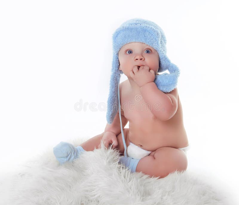 El pequeño bebé lindo es de mirada y que desgasta del sombrero azul fotografía de archivo El pequeño bebé lindo es de mirada y que desgasta del sombrero azul fotografía de archivo