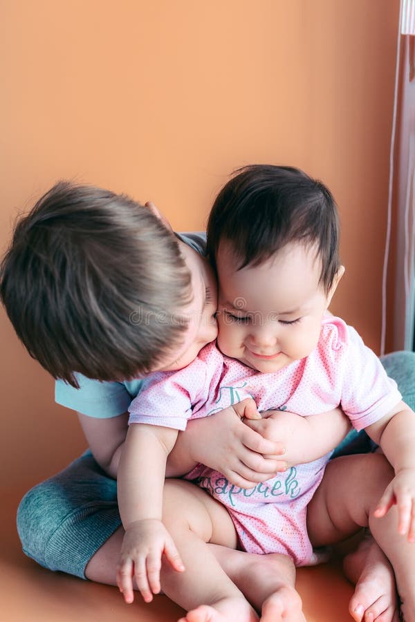 El pequeño hermano feliz que juega abrazos su bebé, muchacho y muchacha de la hermana abraza besos, amor del concepto y el pare fotos de archivo libres de regalías El pequeño hermano feliz que juega abrazos su bebé, muchacho y muchacha de la hermana abraza besos, amor del concepto y el pare fotos de archivo libres de regalías