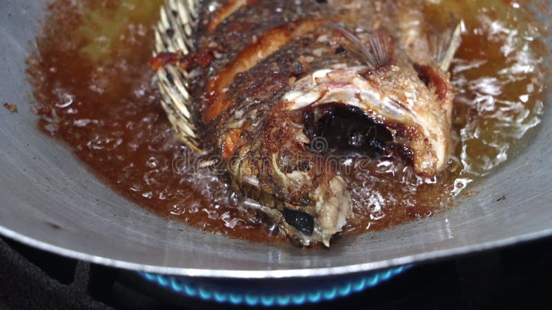 El pez tilapia se frita en aceite en una sartén