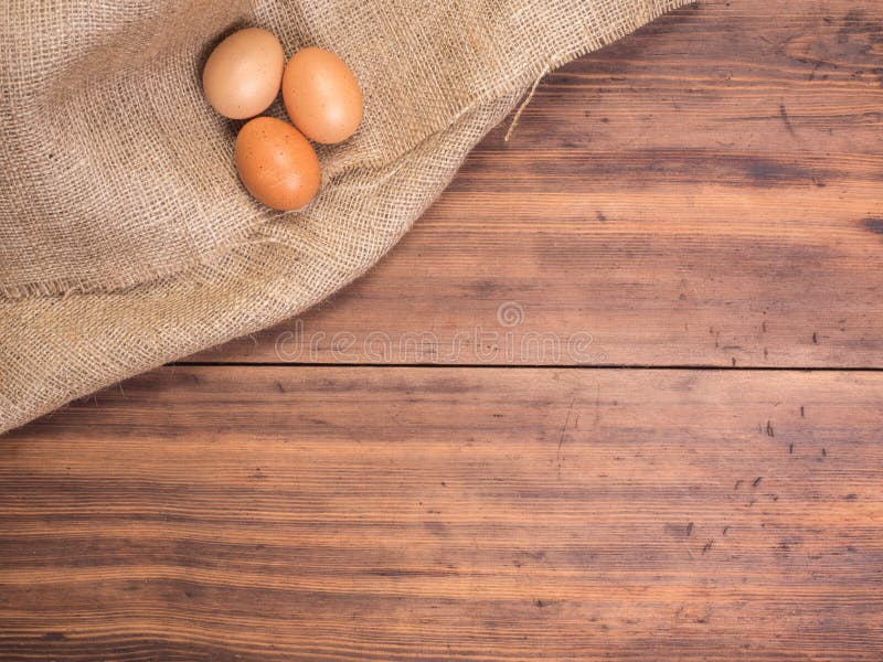 El pollo eggs en los viejos tableros de tabla y fondo de madera rurales del vintage de la arpillera, opinión superior de la foto imagen de archivo El pollo eggs en los viejos tableros de tabla y fondo de madera rurales del vintage de la arpillera, opinión superior de la foto imagen de archivo