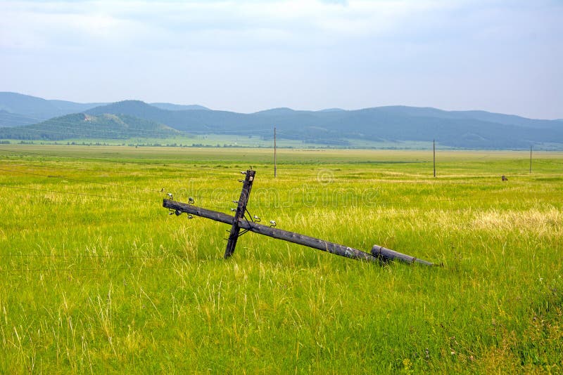 El polo de madera de la línea eléctrica interrumpió y colgó en los alambres, contra el contexto del paisaje de la montaña imagenes de archivo El polo de madera de la línea eléctrica interrumpió y colgó en los alambres, contra el contexto del paisaje de la montaña imagenes de archivo