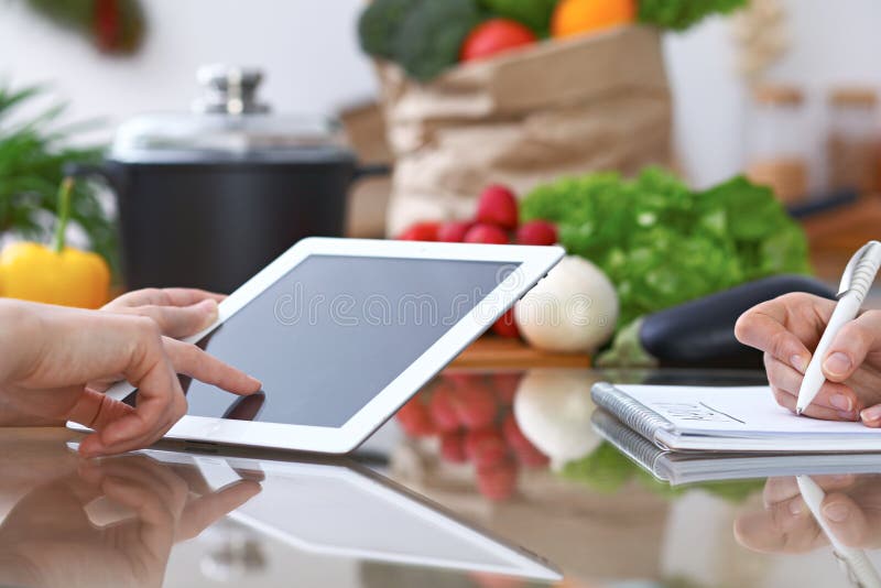 El primer de cuatro manos humanas es gesticula sobre una tableta en la cocina Amigos que se divierten mientras que elige el menú foto de archivo El primer de cuatro manos humanas es gesticula sobre una tableta en la cocina Amigos que se divierten mientras que elige el menú foto de archivo