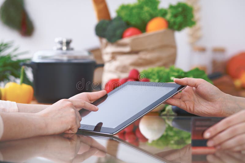 El primer de cuatro manos humanas es gesticula sobre una tableta en la cocina Amigos que se divierten mientras que elige el menú fotos de archivo libres de regalías El primer de cuatro manos humanas es gesticula sobre una tableta en la cocina Amigos que se divierten mientras que elige el menú fotos de archivo libres de regalías