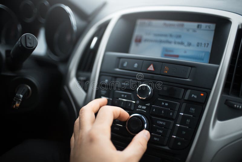 El primer de la mano del hombre ajusta el control de volumen del sistema de audio para el automóvil fotos de archivo