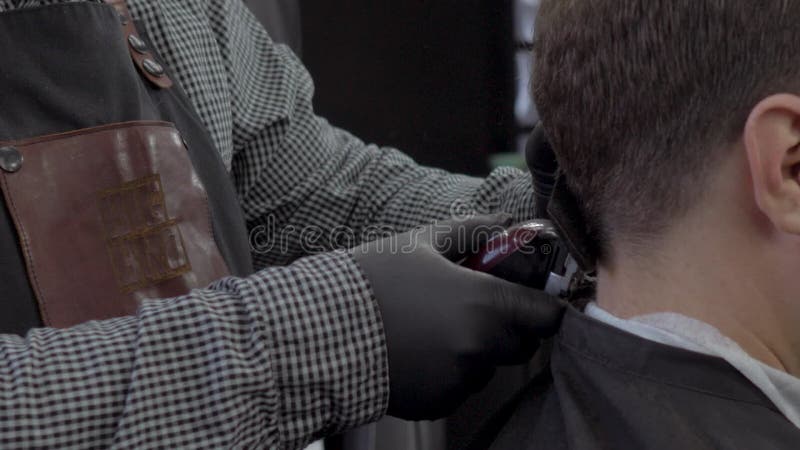 El primer del peluquero corta el pelo por las tijeras en la barber?a Manos del ` s del peluquero en el proceso de trabajo Peluque