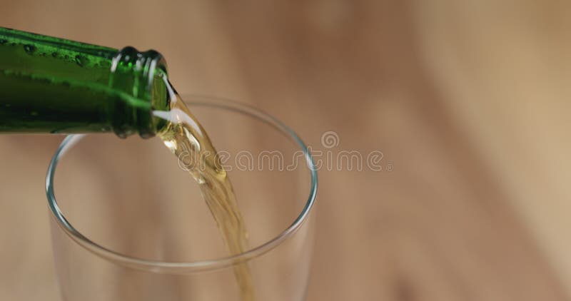 El primer vierte la cerveza de cerveza dorada de la botella verde en el vidrio en la tabla de madera foto de archivo libre de regalías El primer vierte la cerveza de cerveza dorada de la botella verde en el vidrio en la tabla de madera foto de archivo libre de regalías