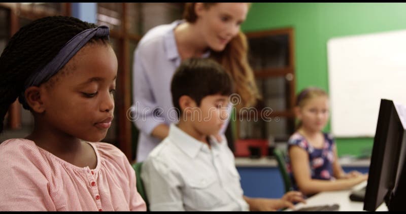 El profesor que ayuda a la escuela embroma en de computadora personal en sala de clase
